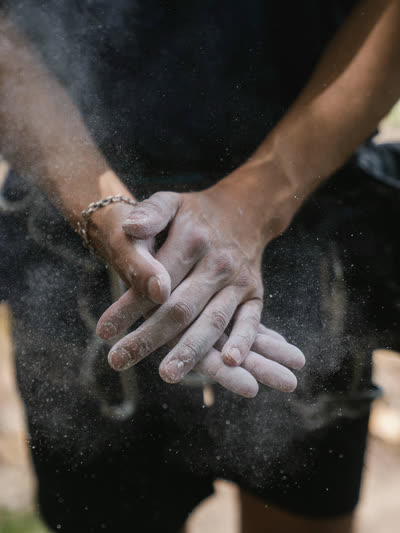 Chalked hands clapping together, dust hanging in the air.