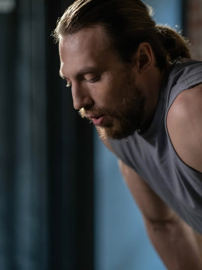Bearded athlete leaning forward with eyes down, catching his breath.