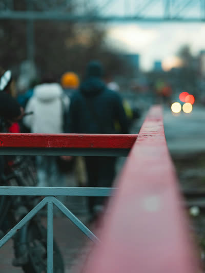 Out-of-focus spectators behind a red barrier at dusk.