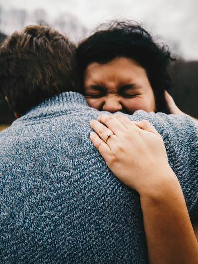 Two people in a tight hug, one face pressed into the other's shoulder.