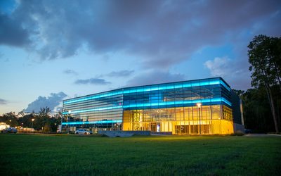 Glass-fronted sports hall lit from inside at dusk