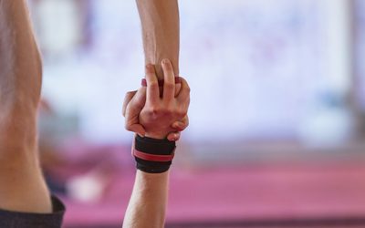 Two hands gripping each other's forearms, one wrist wrapped