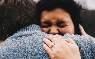 Two people in an embrace, a hand covering one face