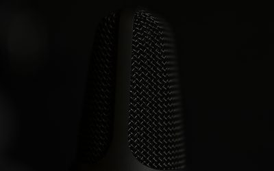 Microphone grille catching a sliver of light on black
